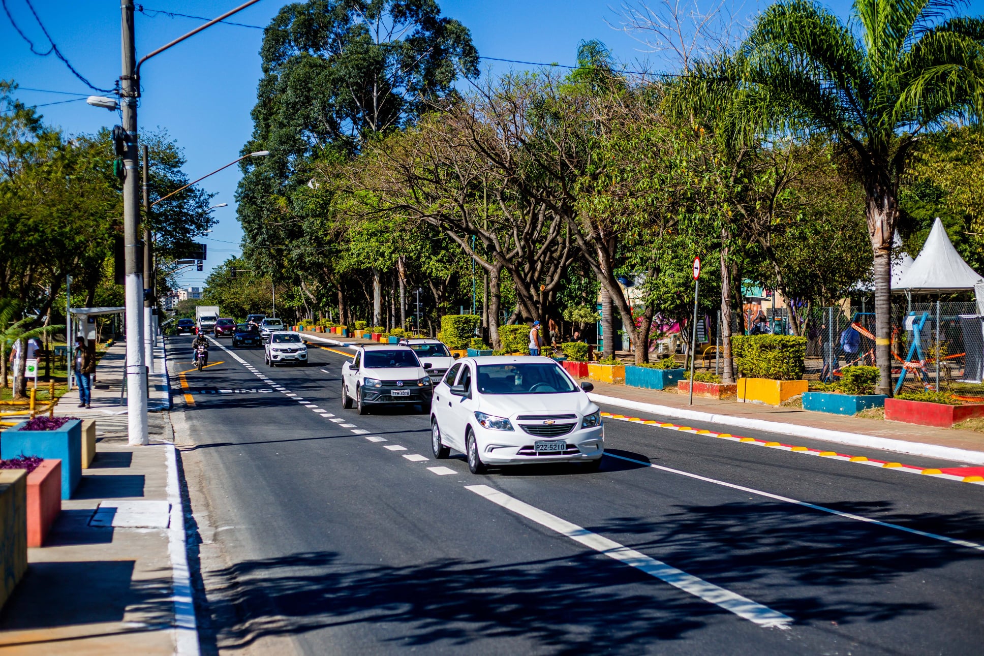 #PraTodosVerem visualiza-se a imagem de um carro branco passando por uma rua.